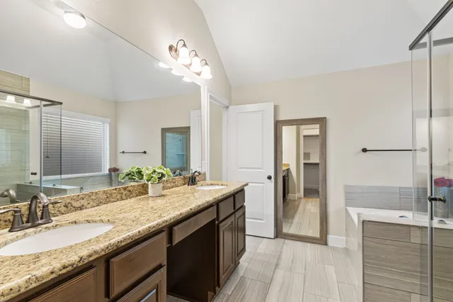 a bathroom with a granite countertop double vanity sink and a mirror