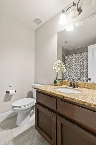 a bathroom with a granite countertop sink a toilet and a mirror