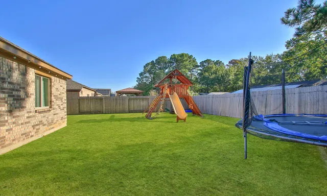 a view of a backyard with a slide trees and wooden fence