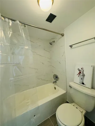 a white toilet sitting next to a bath tub and a shower