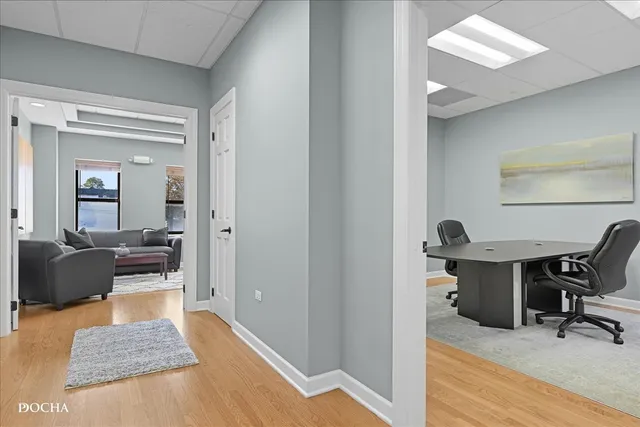 a view of a workspace room with wooden floor and furniture