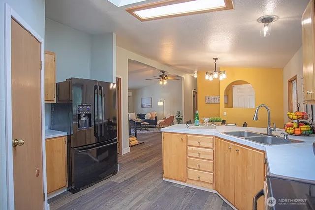 a kitchen with a refrigerator a sink dishwasher a stove and a dining table with wooden floor