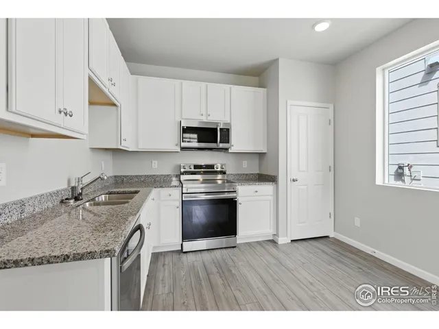 a kitchen with stainless steel appliances granite countertop a stove a sink dishwasher and a microwave oven with white cabinets