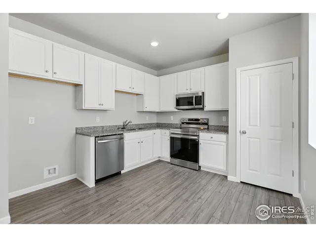 a kitchen with granite countertop white cabinets and stainless steel appliances