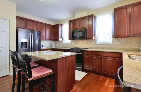 a kitchen with stainless steel appliances granite countertop table chairs sink refrigerator and microwave