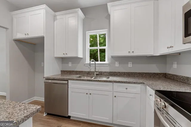 a kitchen with granite countertop white cabinets and a sink