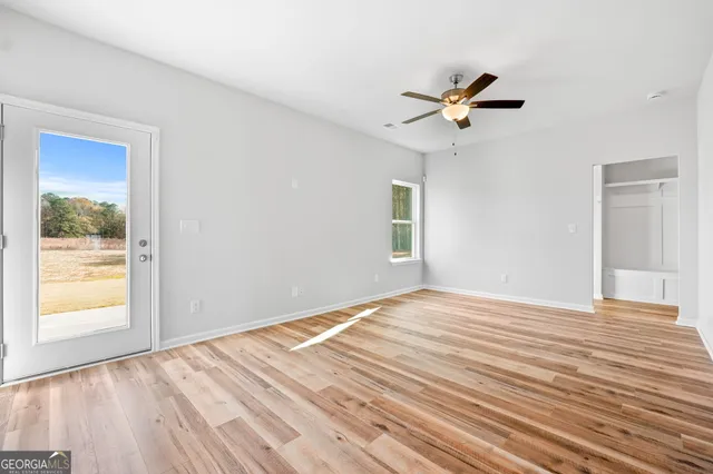 a view of empty room with wooden floor and fan