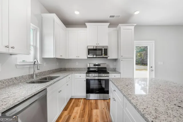 a kitchen with stainless steel appliances granite countertop a sink stove and cabinets