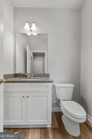 a bathroom with a granite countertop toilet a sink and a mirror
