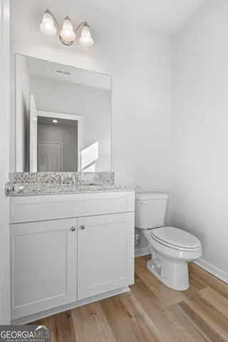 a bathroom with a granite countertop toilet sink and mirror