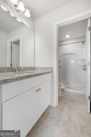 a spacious bathroom with a granite countertop sink a toilet and shower