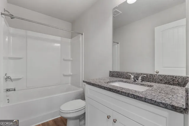 a bathroom with a granite countertop sink a toilet and a bathtub