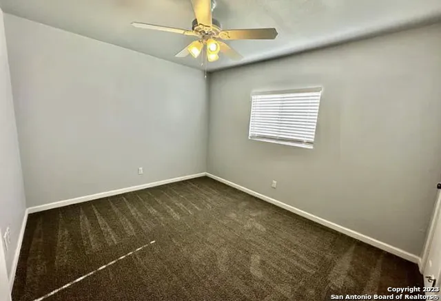 an empty room with a window and a ceiling fan