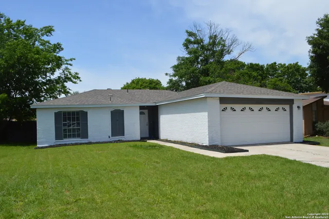 a front view of house with yard and trees in the background