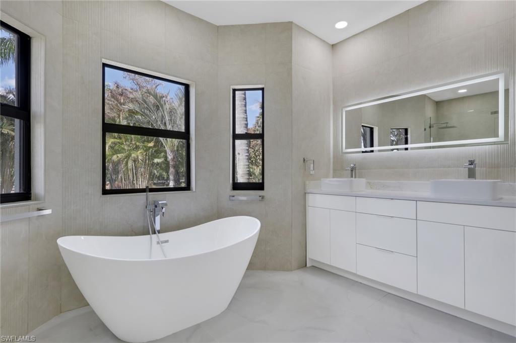 730 29th Street Southwest Naples, FL 34117 - Photo 32 of 50 Full bath with double vanity, a soaking tub, tile walls, and light marble finish flooring