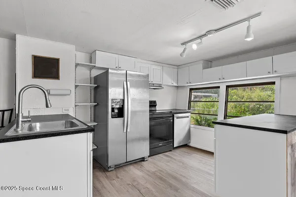 a kitchen with white cabinets and wooden floors