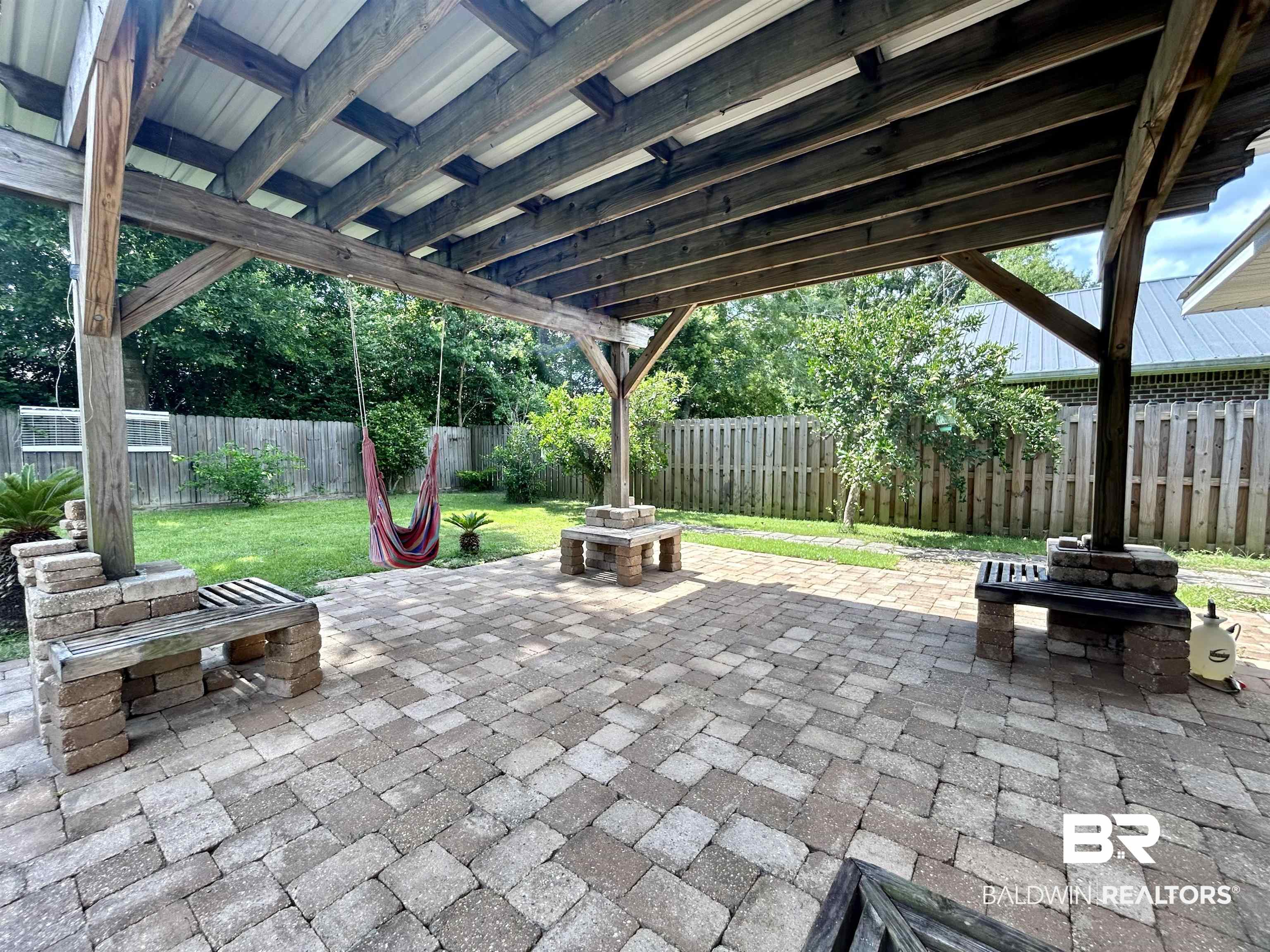7198 Raintree Lane Gulf Shores, AL 36542 - Photo 29 of 33 Expansive paver patio with a wood-framed pergola and metal roof covering
