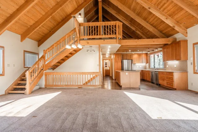a view of an empty room with wooden floor and a fireplace