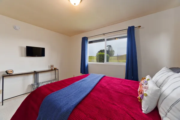 a bedroom with a large bed and a flat tv screen on dresser