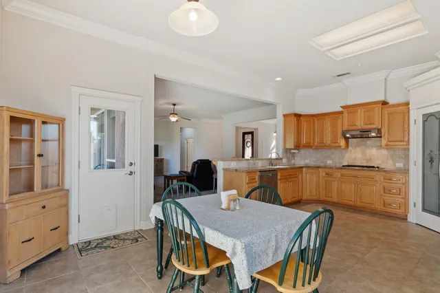 a kitchen with stainless steel appliances kitchen island granite countertop a table chairs sink and cabinets