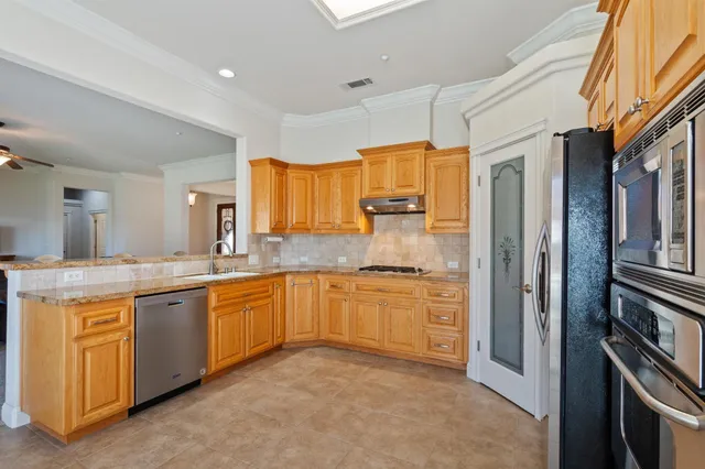 a large kitchen with stainless steel appliances granite countertop a stove a sink dishwasher and a refrigerator
