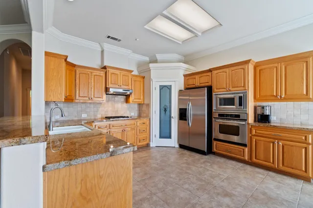 a kitchen with granite countertop a refrigerator and a stove top oven