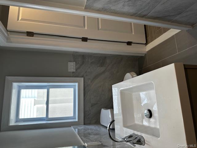 558 Oxford Road Cedarhurst, NY 11516 - Photo 15 of 22 Bathroom with tile walls, vanity, and wainscoting