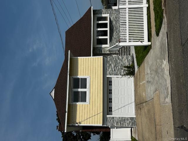 558 Oxford Road Cedarhurst, NY 11516 - Photo 2 of 22 View of front of house with stone siding, an attached garage, driveway, and a shingled roof