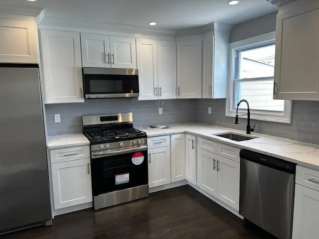 a kitchen with cabinets appliances a sink and a window