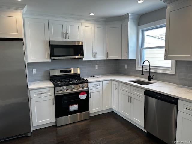 558 Oxford Road Cedarhurst, NY 11516 - Photo 3 of 22 Kitchen with stainless steel appliances, dark wood-style flooring, recessed lighting, tasteful backsplash, and light stone countertops