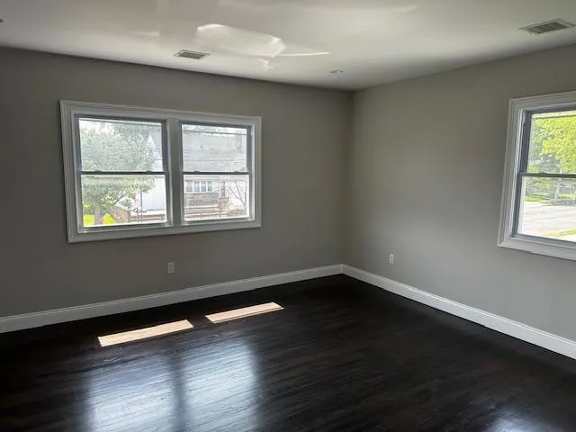 an empty room with wooden floor and windows