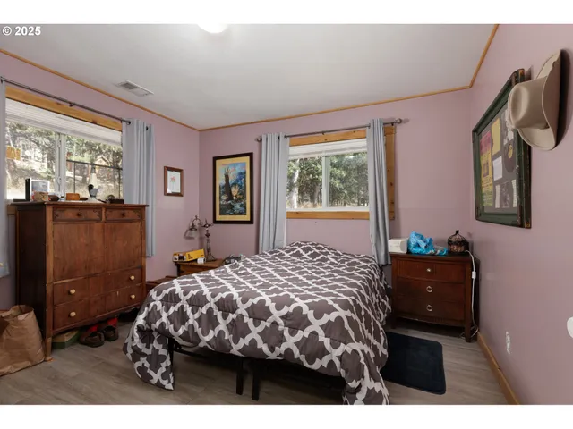 a bedroom with a bed mirror on desk and a window