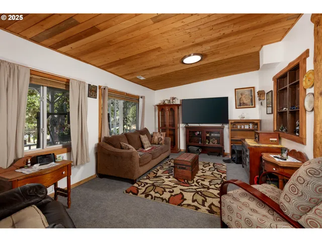a living room with furniture a flat screen tv and floor to ceiling window