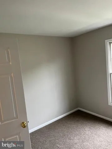 a view of an empty room with closet and a window