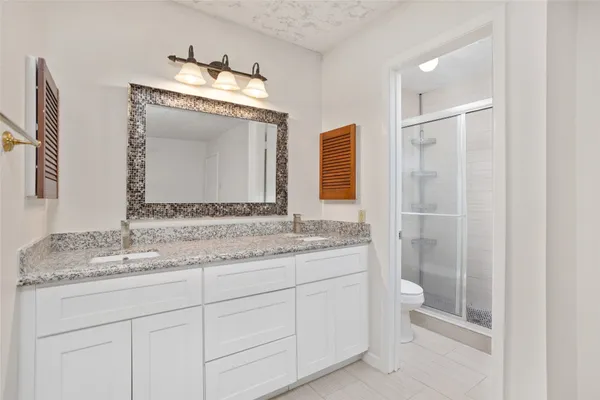 a bathroom with a granite countertop sink a toilet and a mirror