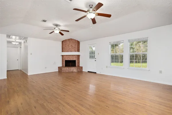 a view of empty room with wooden floor and fan