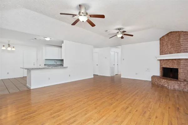 a view of empty room with wooden floor and ceiling fan