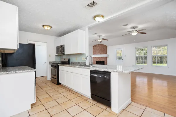 a kitchen with stainless steel appliances kitchen island granite countertop a refrigerator a sink dishwasher a stove with white cabinets