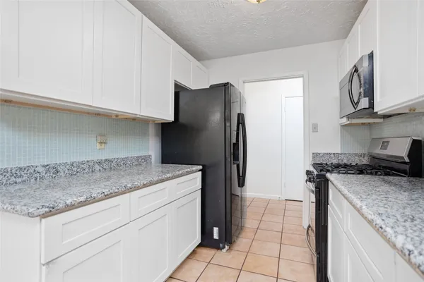 a kitchen with granite countertop a refrigerator and a stove