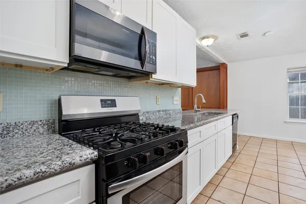 a kitchen with stainless steel appliances granite countertop a sink stove and microwave