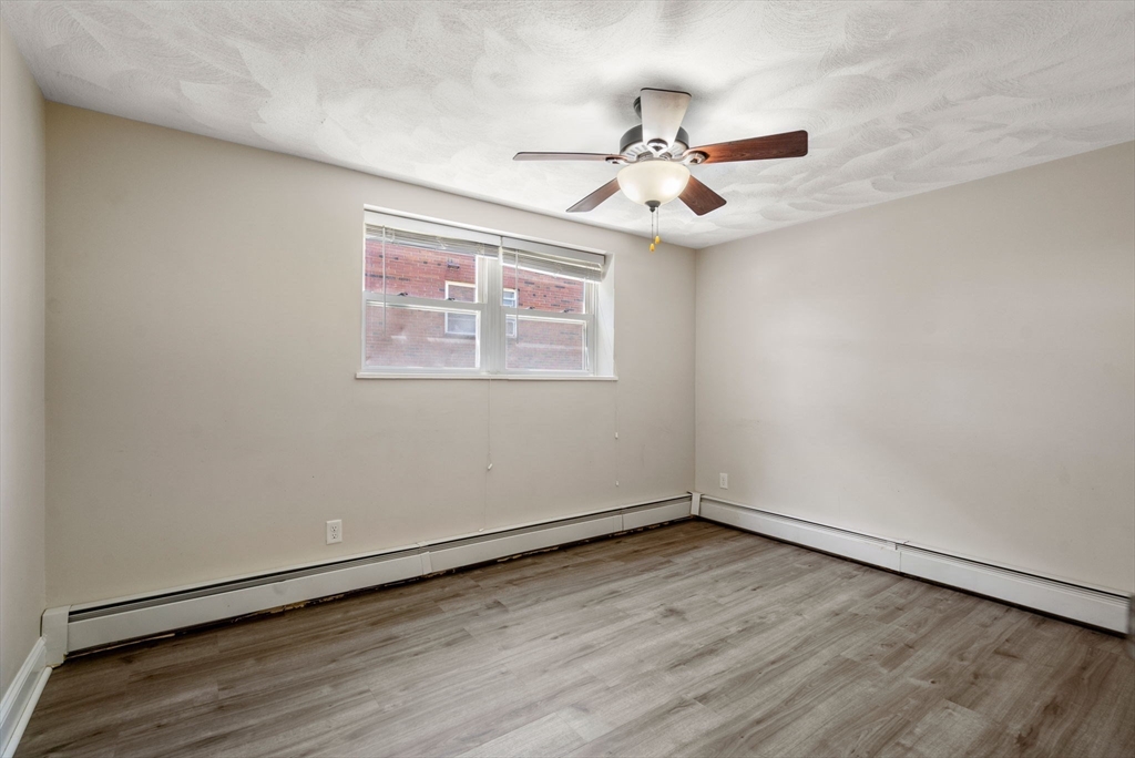 1105 Lexington Street, Unit 41 Waltham, MA 02452 - Photo 9 of 19 an empty room with wooden floor fan and windows