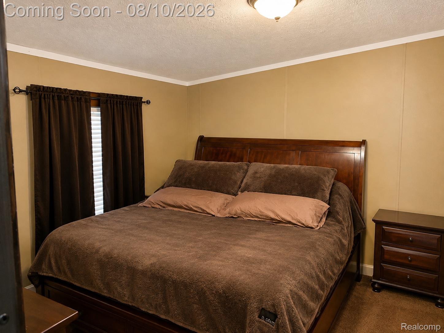 3730 Lapeer Road Port Huron, MI 48060 - Photo 11 of 18 Master bedroom with wood-finish flooring, warm yellow walls, crown molding, and dark wood bed frame with upholstered headboard