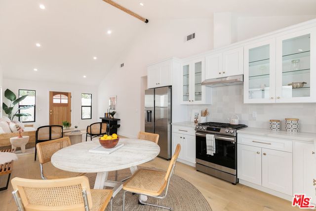 a kitchen with stainless steel appliances granite countertop a stove a sink a dining table and chairs