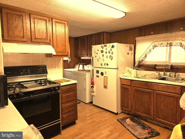 a kitchen with granite countertop a stove a sink and a refrigerator