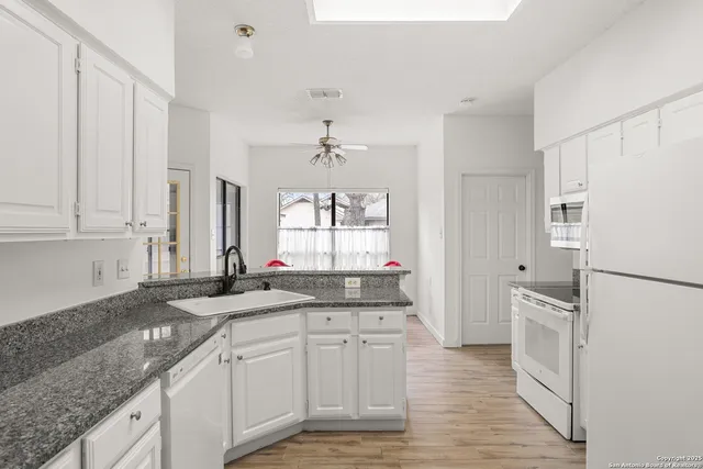 a kitchen with granite countertop a sink cabinets stainless steel appliances and a counter space