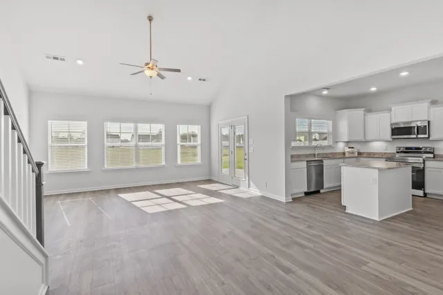 a view of an empty room with window and wooden floor