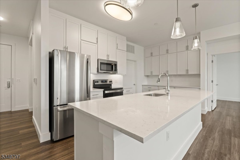 450 Springfield Avenue, Unit 301 Berkeley Heights, NJ 07922 - Photo 4 of 26 a kitchen with kitchen island a sink stainless steel appliances and wooden floor