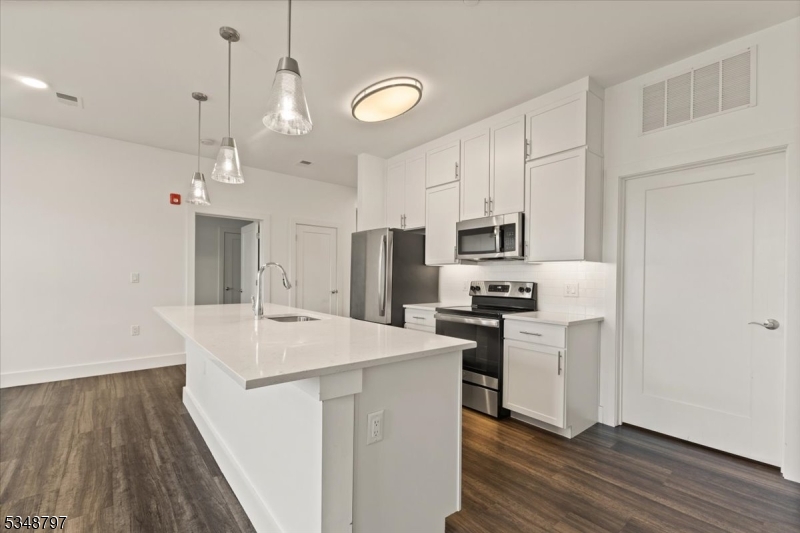 450 Springfield Avenue, Unit 301 Berkeley Heights, NJ 07922 - Photo 5 of 26 a kitchen with stainless steel appliances a stove a refrigerator a oven a sink with wooden floor