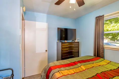 a bedroom with a bed and a flat tv screen on dresser