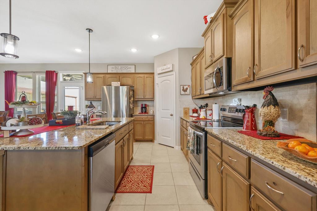 2375 County Road 4010 Decatur, TX 76234 - Photo 7 of 34 Kitchen with stainless steel appliances, light tile patterned floors, light stone counters, decorative backsplash, and hanging light fixtures